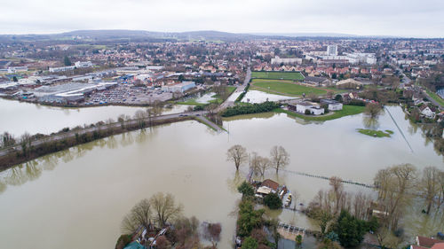 Aerial view of flooded river and cityscape against sky