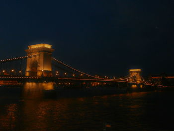 Illuminated suspension bridge over river at night