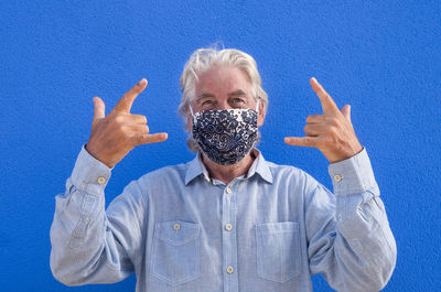 Portrait of man gesturing against blue wall