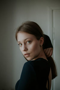 Portrait of beautiful young woman standing against wall at home