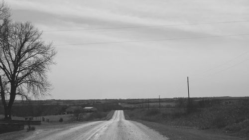 Road by trees against sky