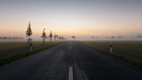 Road by landscape against sky during sunset