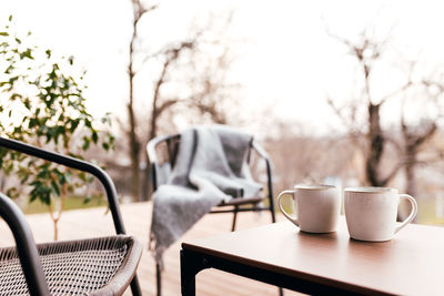 Empty coffee cup on table against trees