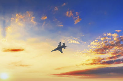 Low angle view of airplane flying against sky during sunset