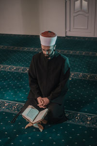 High angle of man reading koran in mosque