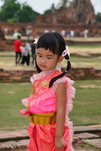 Cute girl wearing traditional clothing standing on field