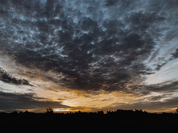 Silhouette landscape against dramatic sky during sunset