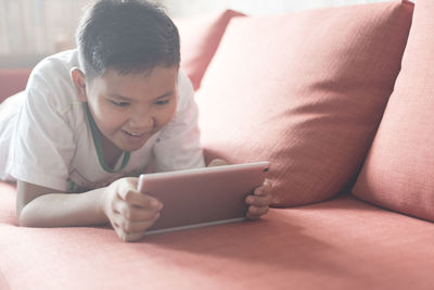 Close-up of boy using laptop on bed at home