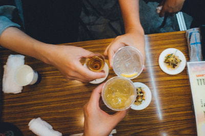 Midsection of woman holding drink on table