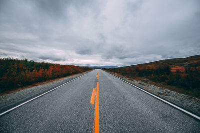 Empty road against cloudy sky