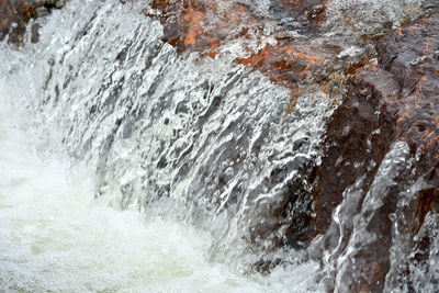 Close-up of waterfall along rocks in winter