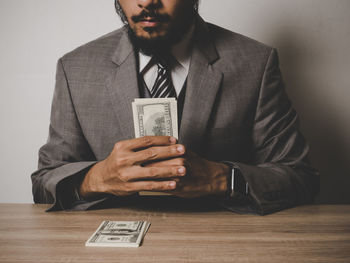 Midsection of businessman with paper currency at table