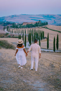 Rear view of people walking on field against sky