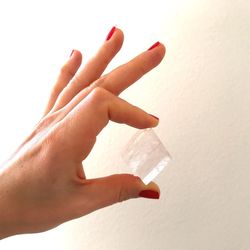 Close-up of hand holding paper over white background