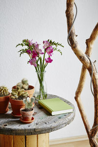 Close-up of flower vase on table against wall at home