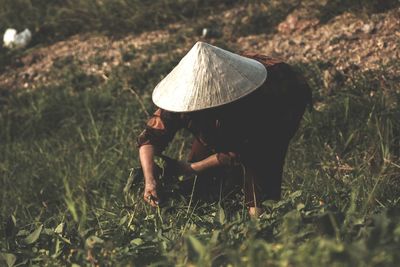 Mature woman wearing hat while working on farmland 