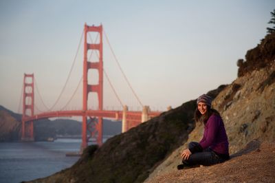 Man sitting on bridge against sky