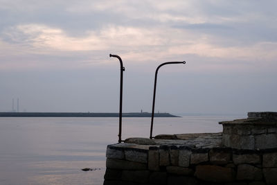 Street light by sea against sky during sunset