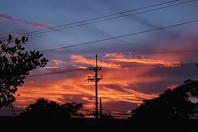 Low angle view of silhouette electricity pylon against sky