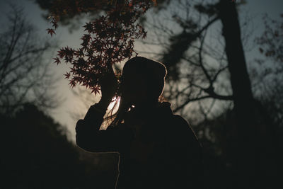 Silhouette woman standing by tree against sky