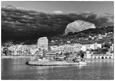 Buildings by sea against sky in city