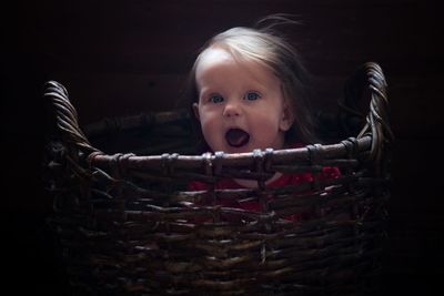 Portrait of cute girl with mouth open sitting in wicker basket