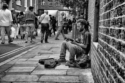 Group of people sitting on sidewalk in city