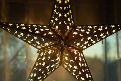 Close-up of illuminated star shape lighting equipment hanging at home