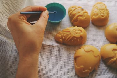 Cropped hand preparing easter eggs on textile