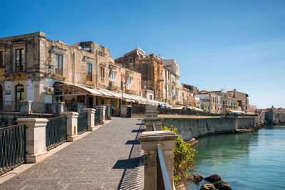 Buildings at waterfront against blue sky