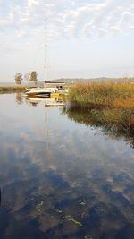 Sailboats moored in lake against sky