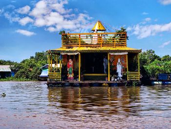 Traditional building by lake against sky