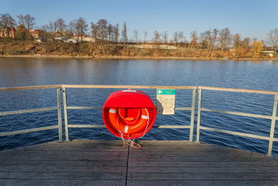 Red umbrella on lake against sky