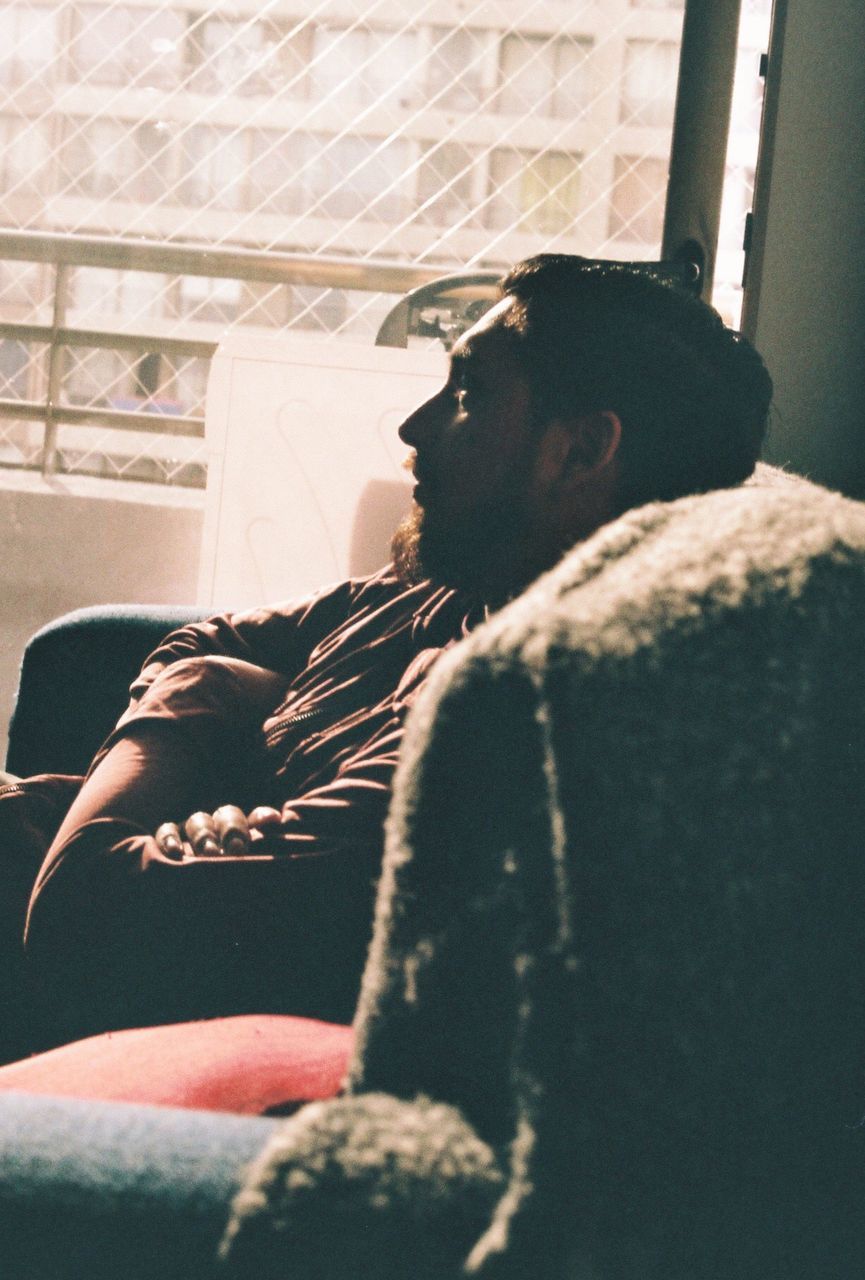 SIDE VIEW OF MAN RELAXING ON BED