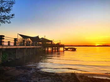 Pier in sea at sunset