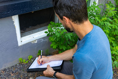 Side view of man holding plants in yard