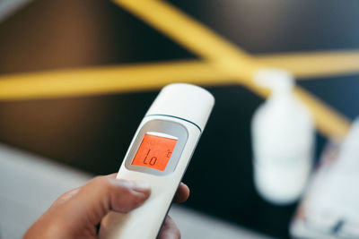 Cropped hand of person holding infrared thermometer