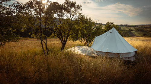 Tent on field against sky during sunset