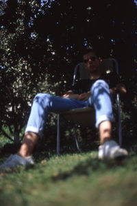 Full length of young man sitting on land in forest