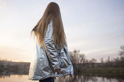 Rear view of woman looking at lake against sky