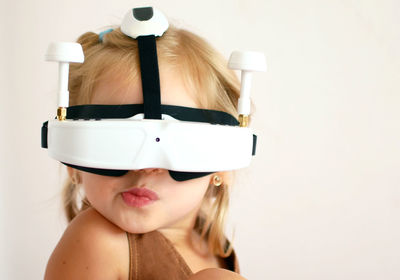 Close-up of girl wearing virtual reality simulator against wall