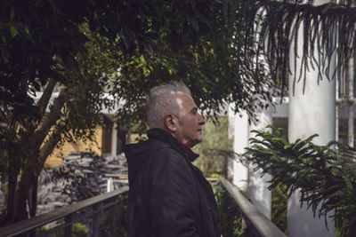 Side view of man standing against trees