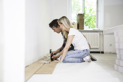 Side view of couple doing carpentry work at home