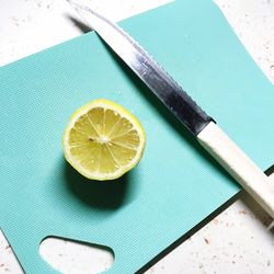 High angle view of lemon by knife on cutting board