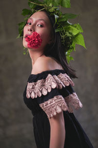 Portrait of young woman standing against red plant