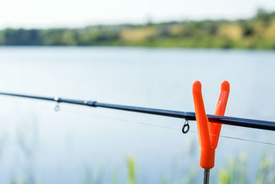 Close-up fishing rod on lake against sky