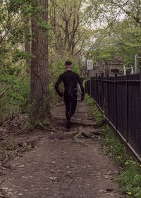 Rear view of man walking on footpath in forest