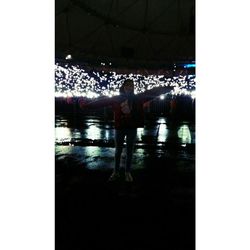 People standing in illuminated water at night