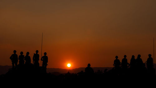 Silhouette group of special forces sodiers standing and sit on tank with over the sunset background,