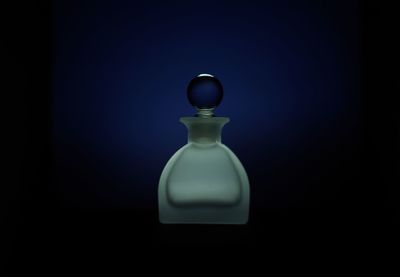 Close-up of perfume bottle against blue background